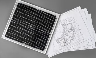 Planimetrie architettoniche e pannello solare su un tavolo, vista ravvicinata.